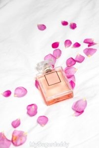 Vemos un frasco de perfume tirado sobre la cama con petalos de rosas. Muy feminino y muy atento.