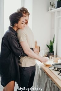 Relación nueva: Amor puro Relación nueva: Podemos ver a una mujer abrazando de espaldas a un hombre. El esta levemente girado hacia atrás y la mira. Parece que él le esta haciendo el desayuno.
