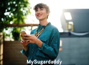 Citas en línea: Sugar Baby  Citas en línea: Podemos ver a una mujer joven que esta feliz con su celular a la mano. Es bella y disfruta del sol.
