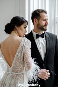 Consejos de estilismo: En la imagen vemos a una pareja Sugar. Están vestidos formalmente. El Sugar Daddy lleva puesto un traje formal y ella un vestido hermoso. 