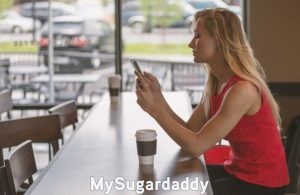 Mujeres jóvenes solteras: Online Mujeres jóvenes solteras: Vemos a una mujer joven utilizando su teléfono celular. Esta en un restaurante. No va acompañada, es decir, esta sentada sola sin compañía. Tal vez esté buscando al hombre ideal en una plataforma online.