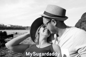 Vida en pareja: Vemos a una pareja teniendo un momento feliz. Están disfrutando de un día en la playa. Además de ser feliz, también es romántico, ya que están a punto de darse un beso.